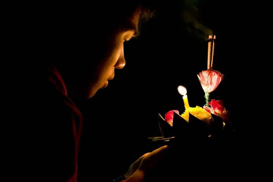 A man prepares to release a krathong into the river